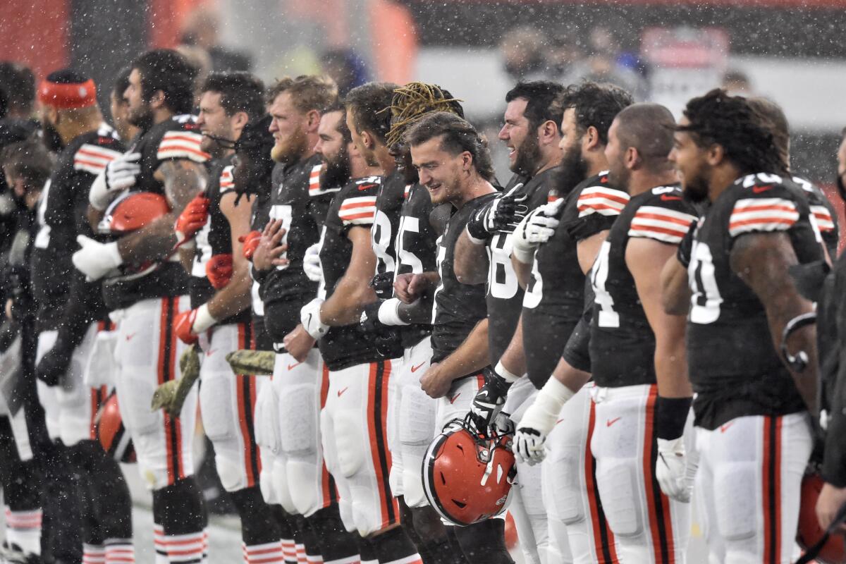 Jugadores de los Browns de Cleveland escuchan el himno nacional bajo la lluvia antes del partido frente a los Texans.