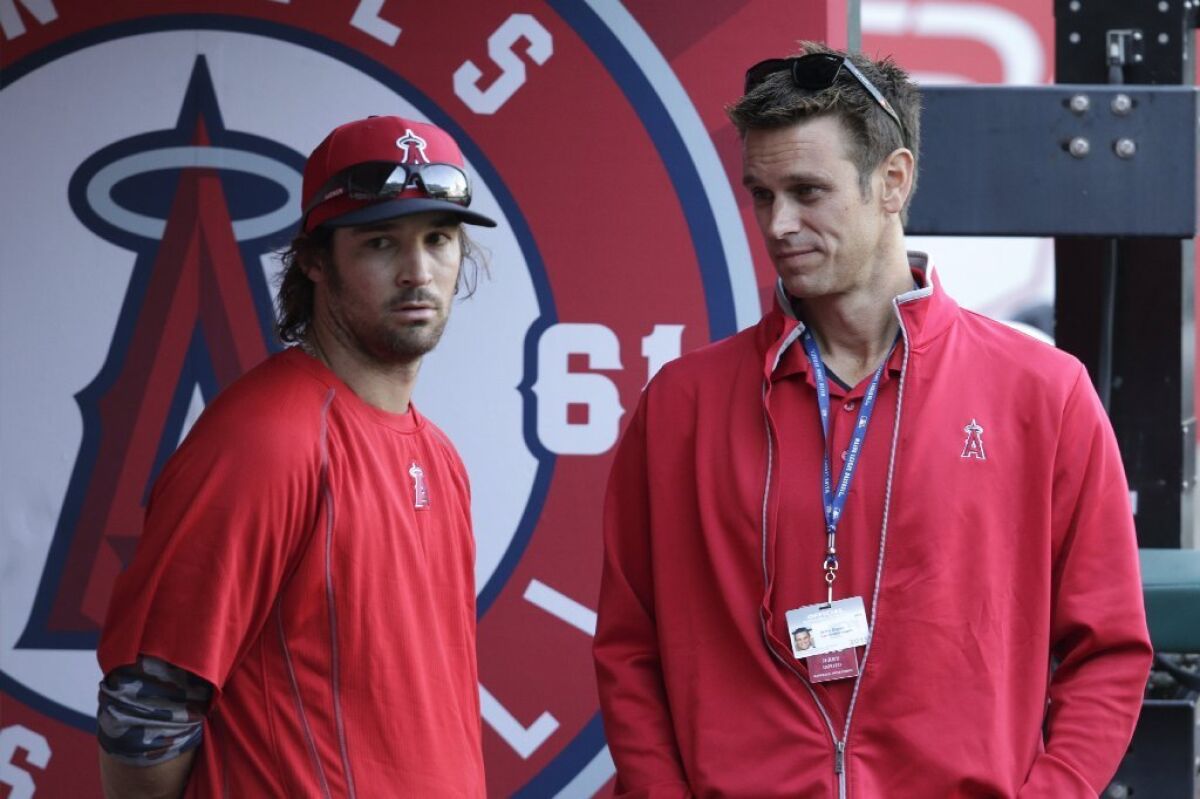 Angels pitcher C.J. Wilson talks with General Manager Jerry Dipoto before a game against the Kansas City Royals on April 11.