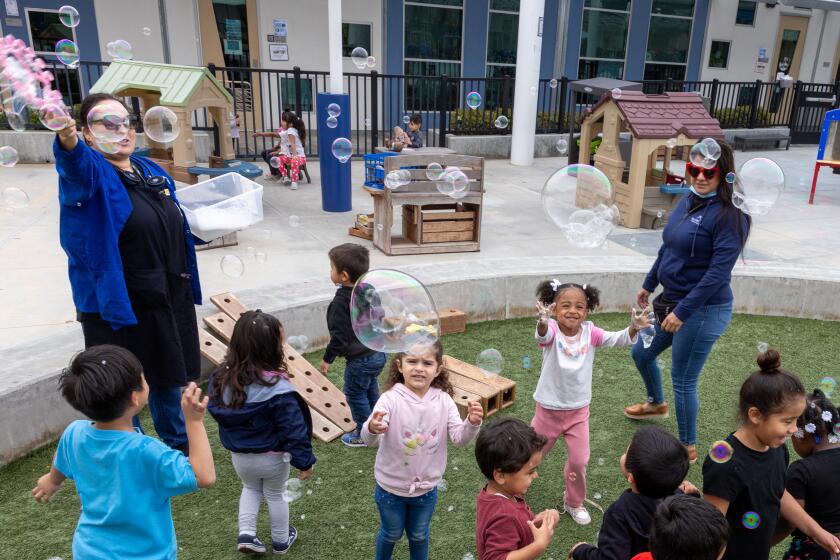 Students play with bubbles on a playground.