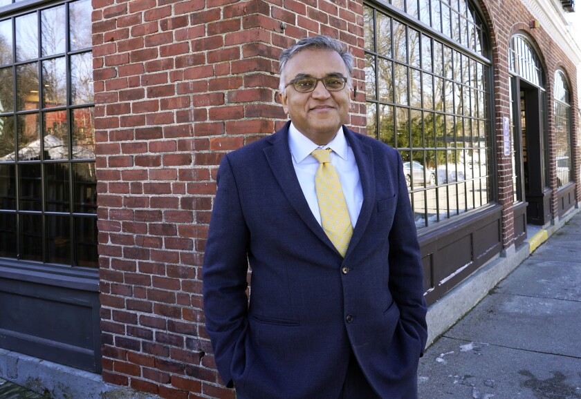 Ashish Jha stands before a windowed brick wall.