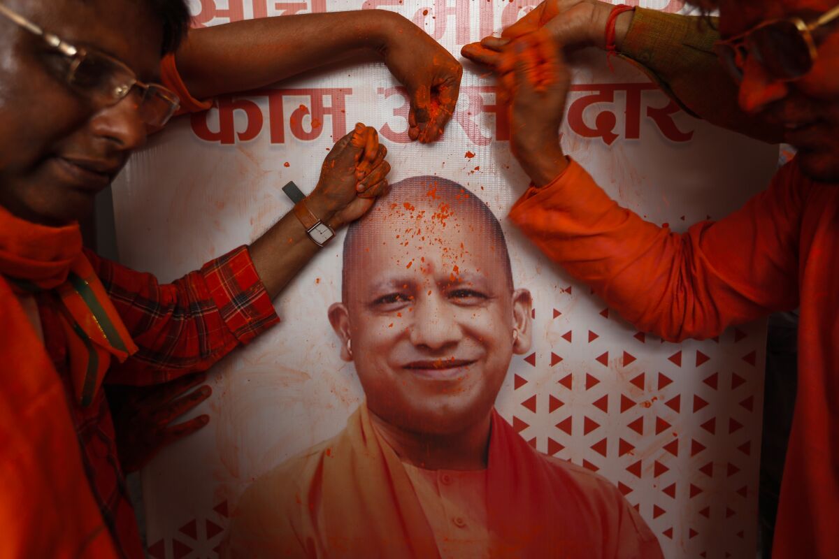 Bharatiya Janata Party (BJP) workers put colored powder on a photograph of incumbent chief minister Yogi Adityanath as they celebrate early leads for the party as election officials count votes after Uttar Pradesh state elections in Lucknow, India, Thursday, March 10, 2022. India's election authority started counting votes Thursday in five states' elections that are a crucial test for Prime Minister Narendra Modi’s Hindu nationalist Bharatiya Janata Party before national elections in 2024.All results are expected to be available later in the day. (AP Photo/Rajesh Kumar Singh)