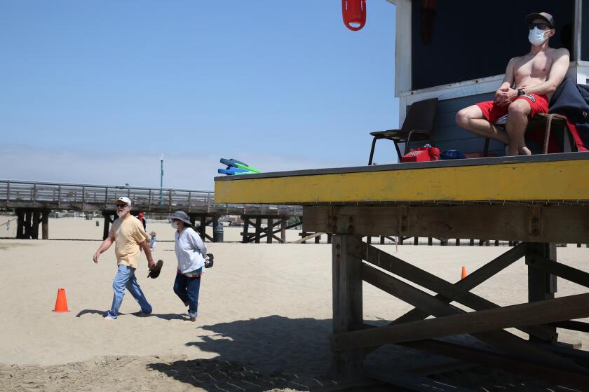 ORANGE COUNTY, CA - MAY 11: Nathan Thompson, right, works as a lifeguard in Seal Beach on Monday, May 11, 2020 in Orange County, CA. Seal Beach reopened to active use on Monday and will only be open during daylight hours Monday through Thursday. (Dania Maxwell / Los Angeles Times)