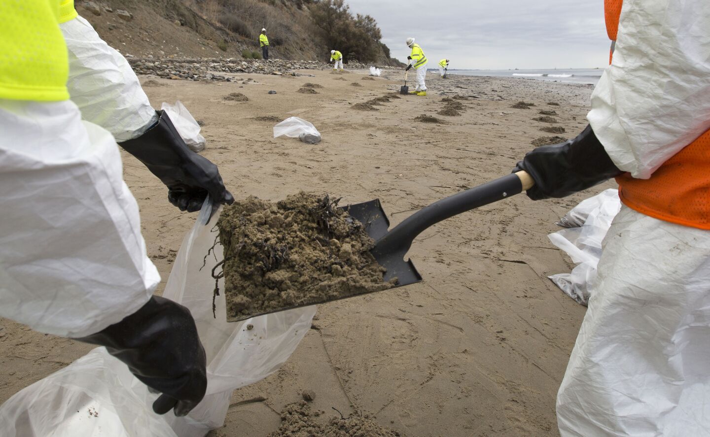 Patriot Environmental Services employees bag oil-contaminated sand on the shoreline at Refugio State Beach.