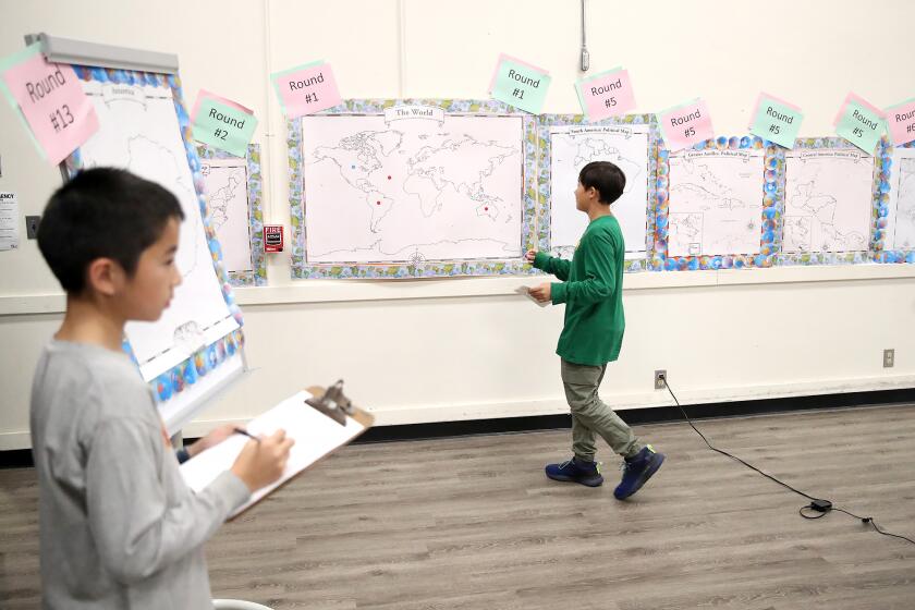 Contestant Nathen Mercer, in green, walks to place a sticker on a world map with confidence, during 5th & 6th grade Geography Bee at Lincoln Elementary on Thursday.