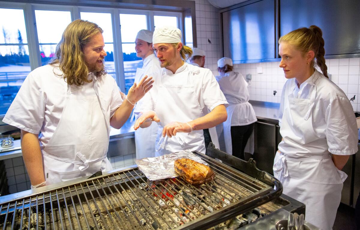 Head chef Magnus Nilsson talks to his staff while preparing a saddle of veal over an open fire at Fäviken.