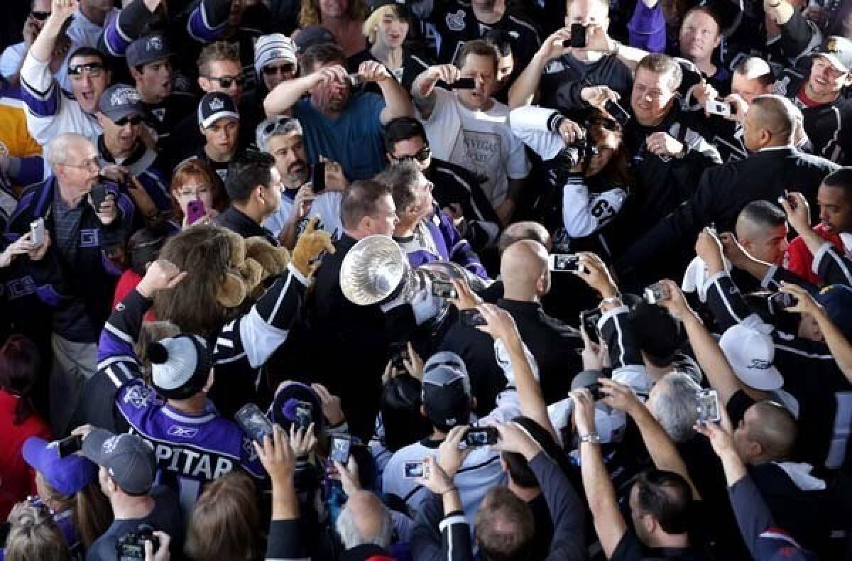 Kings fans cheer as they take pictures of the Stanley Cup outside Staples Center on Saturday before the season opener.