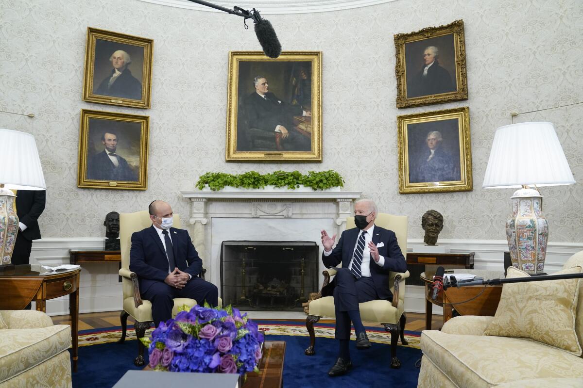 President Biden and Israeli Prime Minister Naftali Bennett, wearing masks, sit in the Oval Office.
