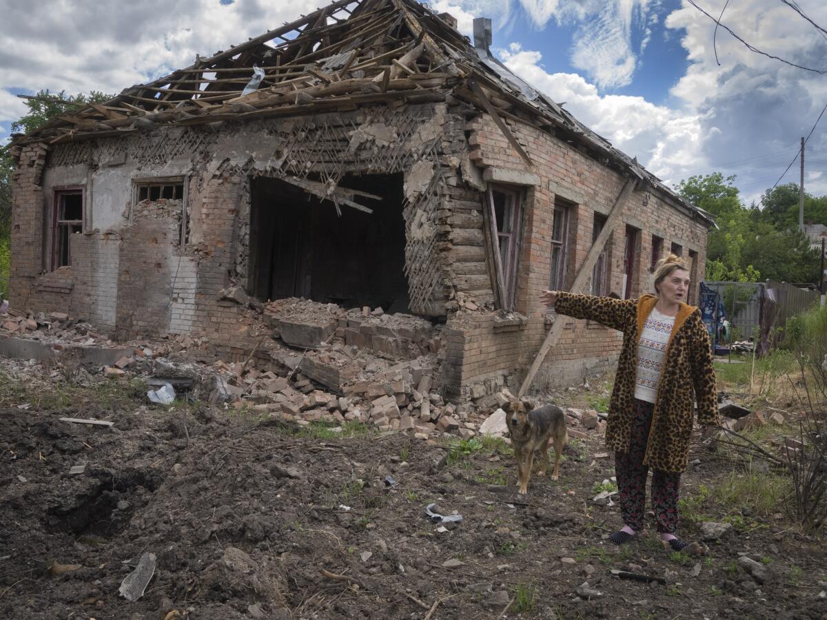La residente local Tetyana apunta a su casa dañada por el cañoneo ruso en Bajmut,
