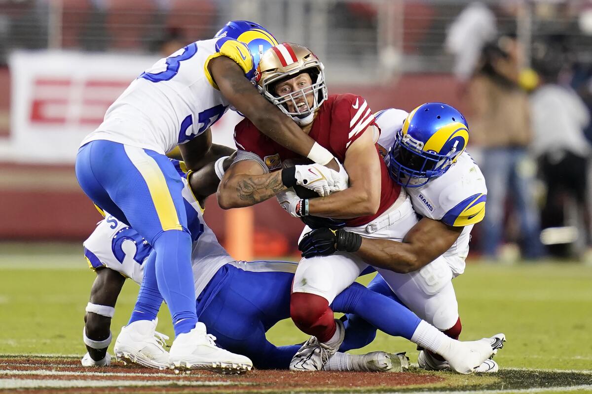 San Francisco 49ers tight end George Kittle, middle, is tackled by the Rams in the second half.