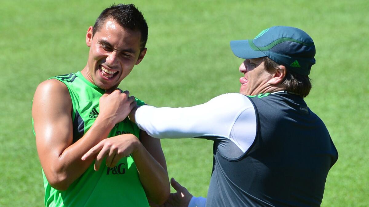Mexico's Coach Miguel Herrera, right, jokes with defender Paul Aguilar during a team training session Saturday.