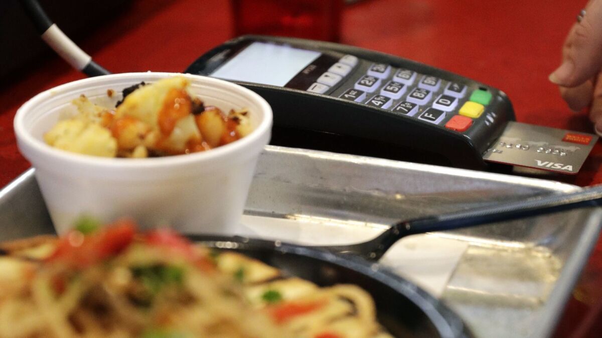 A customer uses a credit card to pay for a meal at Peli Peli Kitchen in Houston.