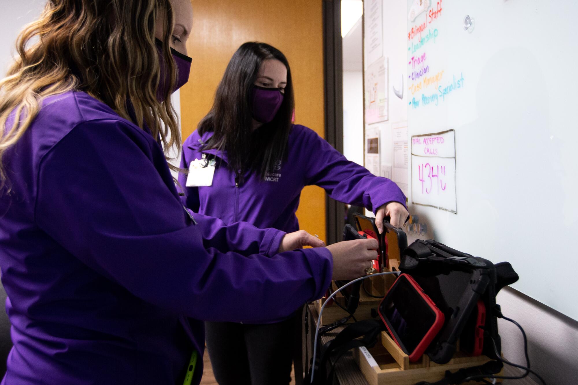 Two women in purple shirts prep emergency response gear.