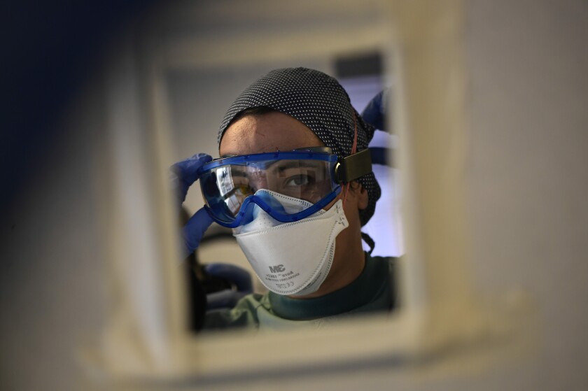 A member of the medical team puts on PPE, in the ICU department of the Clinica Universitaria, in Pamplona, northern Spain, Wednesday, Jan. 12, 2022. Spain’s medical community has scored a victory after a court ordered that a regional government compensate doctors with up to 49,000 euros ($56,000) for having to work without personal protection suits during the devastating early months of the pandemic. (AP Photo/Alvaro Barrientos)