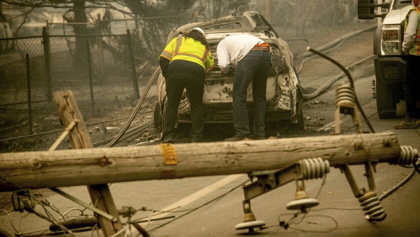 Eric England, right, searches through a friend's vehicle after the Camp fire burned through Paradise, Calif.