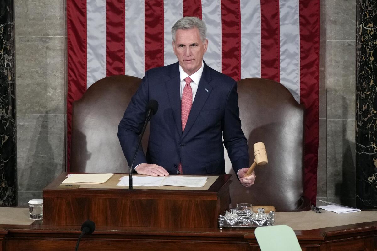Speaker Kevin McCarthy holding a gavel as he stands at his desk in the House chamber