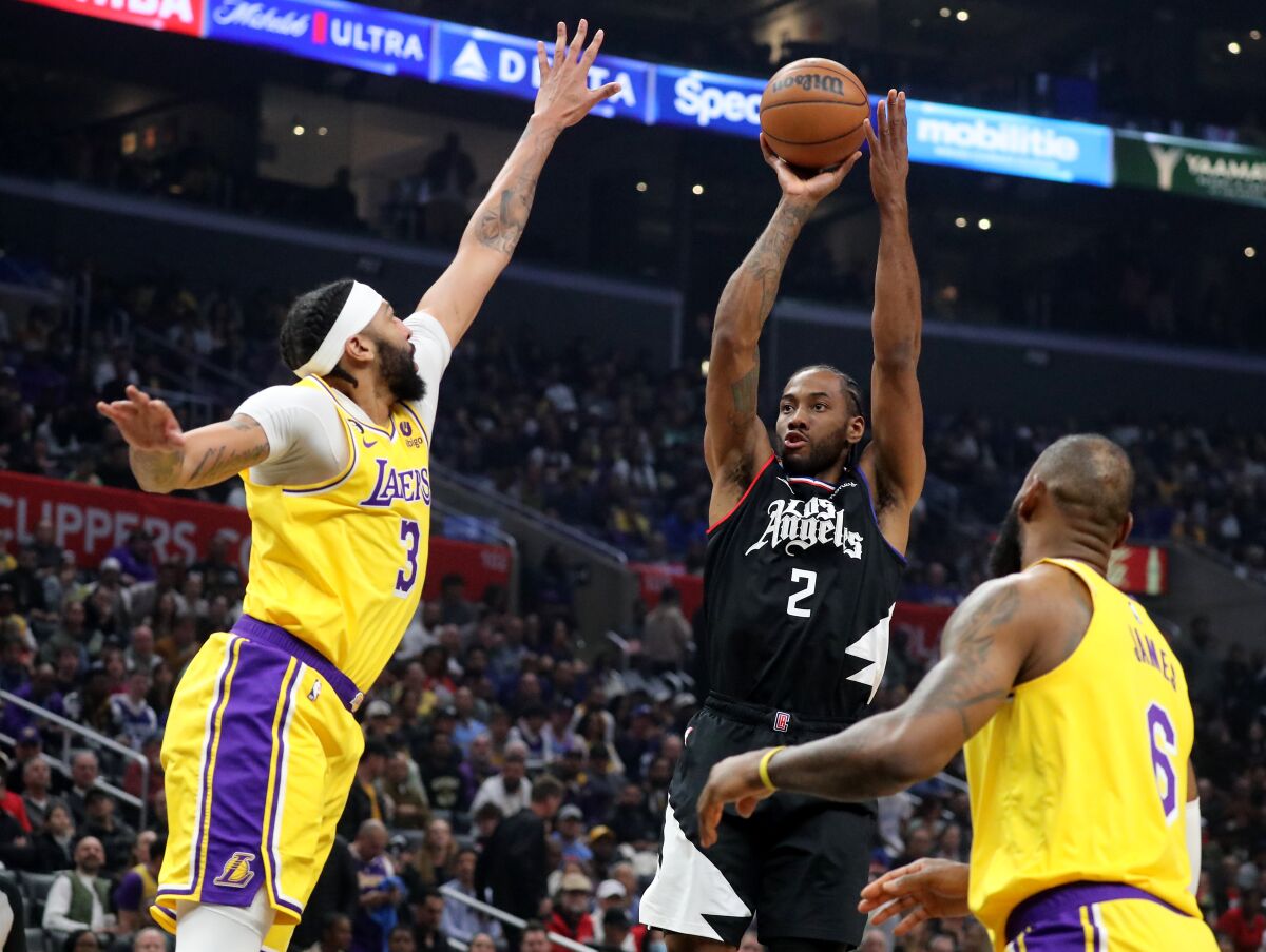 Clippers forward Kawhi Leonard shoots and scores over Lakers defenders Anthony Davis, left, and LeBron James.