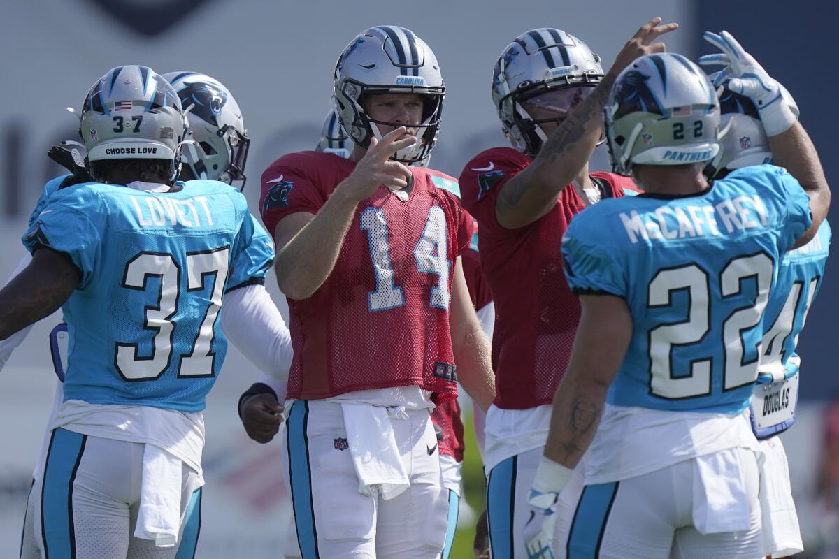 Carolina Panthers quarterback Sam Darnold (14) greets teammates running back John Lovett (37) and running back Christian McCaffrey (22) during an NFL football joint practice with the New England Patriots, Tuesday, Aug. 16, 2022, in Foxborough, Mass. (AP Photo/Steven Senne)