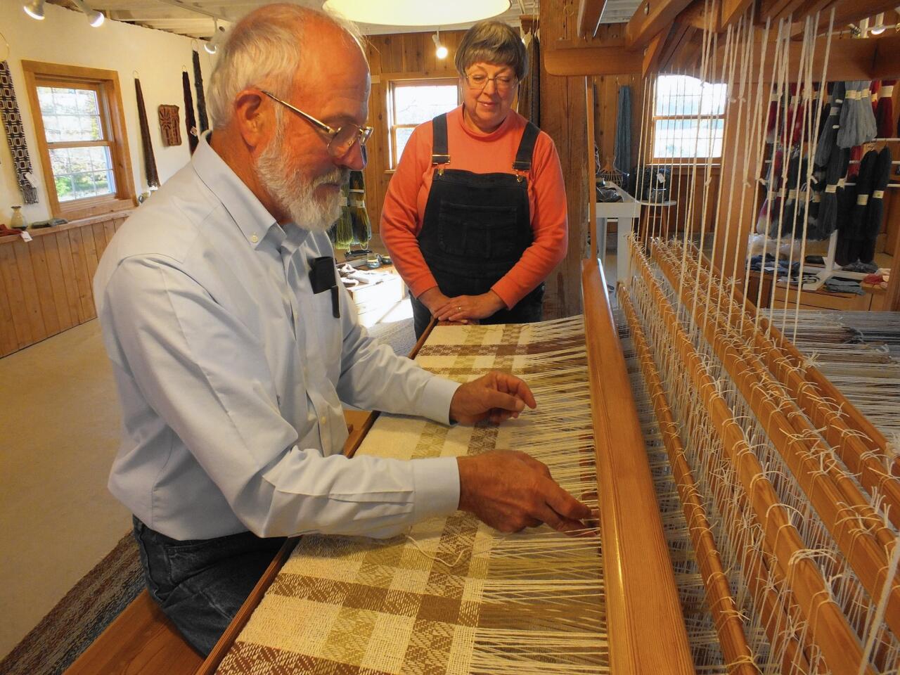 On a large loom, Dick Regnery of Whitefish Bay Farm crafts a wool, blanket while his wife, Gretchen, watches.