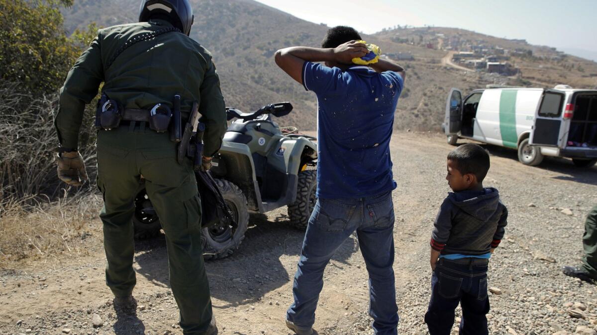 A Guatemalan father and son, who crossed the U.S.-Mexico border illegally, are apprehended by a U.S. Border Patrol agent in San Diego on June 28.