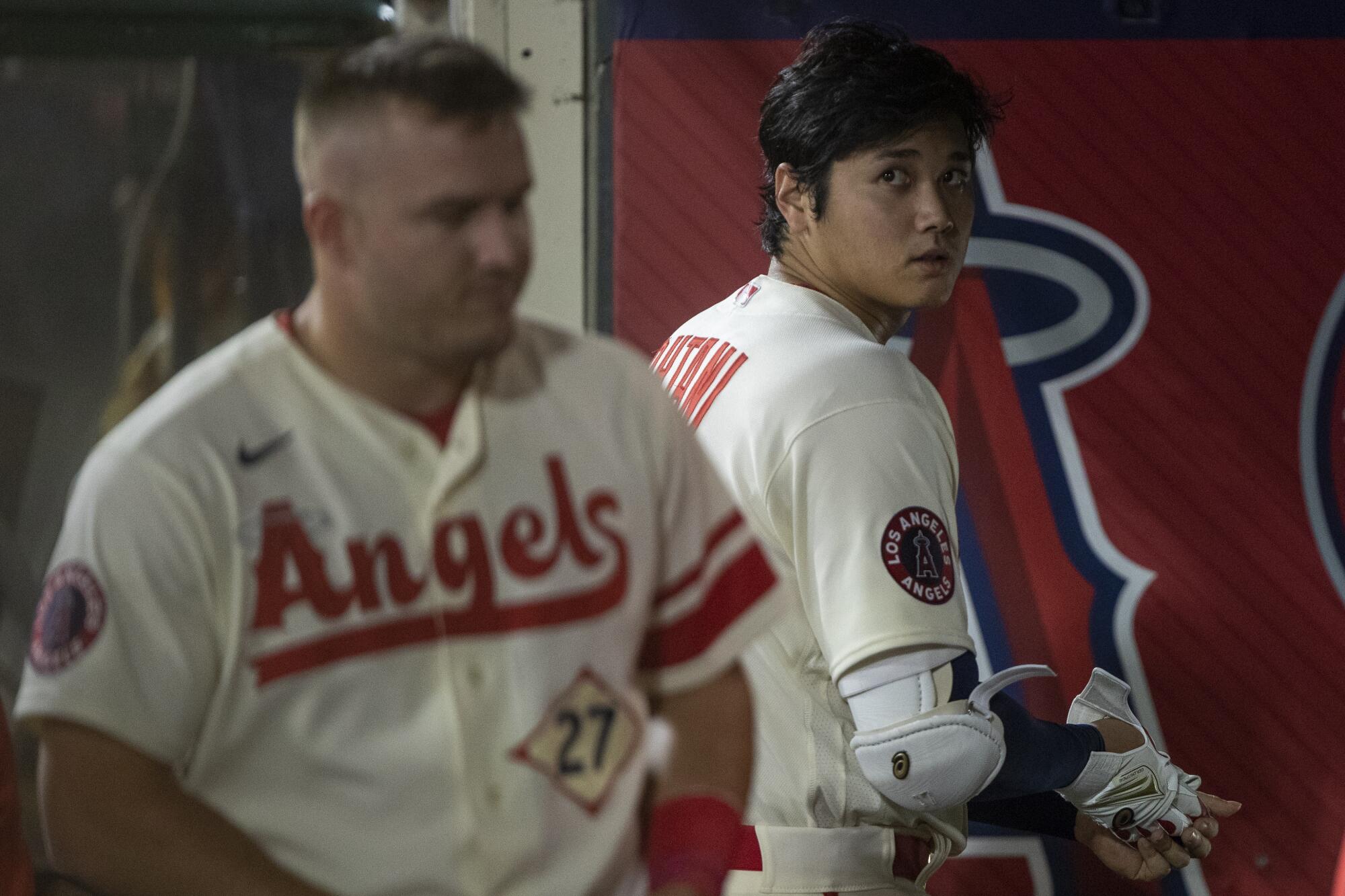 Los Angeles Angels' Shohei Ohtani, right, looks back in the dugout.