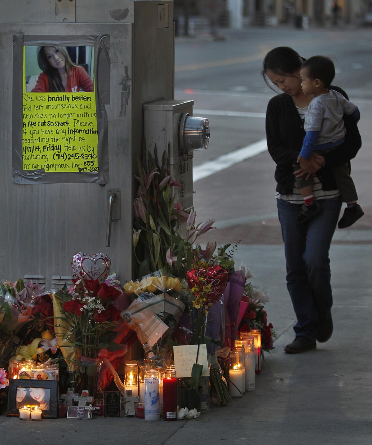 Fountain Valley resident Nga Doan, right, and her 21-month-old son, Frederik Doan, look at flowers and candles left outside the Crosby nightclub in Santa Ana. Doan's niece, Kim Pham, 23, was beaten unconscious at the site over the weekend.
