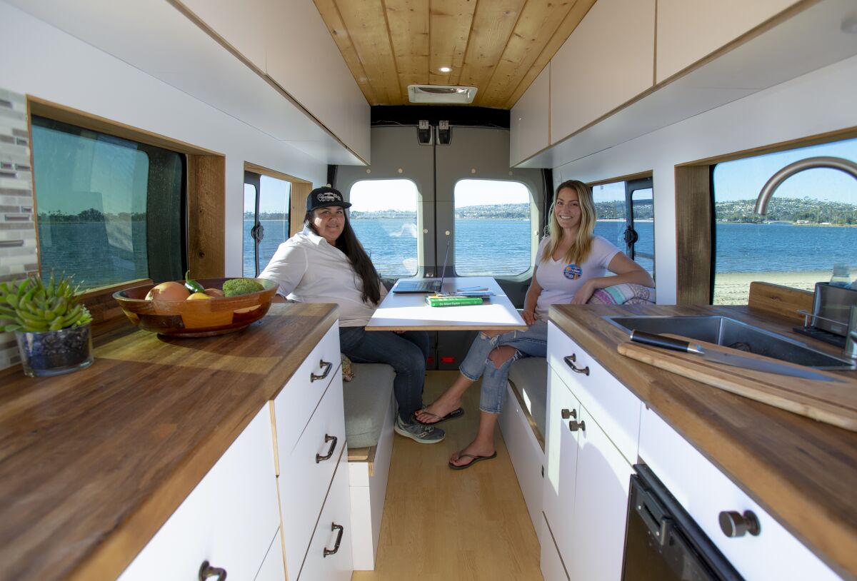 Breanne Acio (left) and Jessica Shisler, co-founders of The Vanlife App, relax in Acio's converted van after a business meeting.