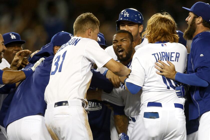 Howie Kendrick is mobbed by his teammates after delivering a walk-off victory for the Dodgers with a two-run single in the bottom of the ninth inning. The Dodgers beat the Mariners, 6-5.