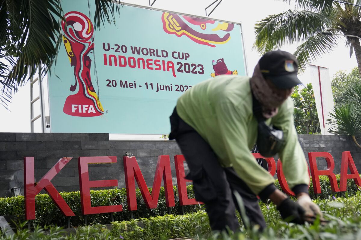 Un trabajadores corta el césped cerca de un anuncio del Mundial Sub-20 en Jakata, Indonesia 