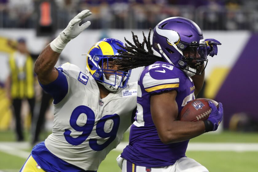 Minnesota Vikings running back Alexander Mattison (25) runs from Los Angeles Rams defensive end Aaron Donald (99) during the second half of an NFL football game, Sunday, Dec. 26, 2021, in Minneapolis. (AP Photo/Bruce Kluckhohn)