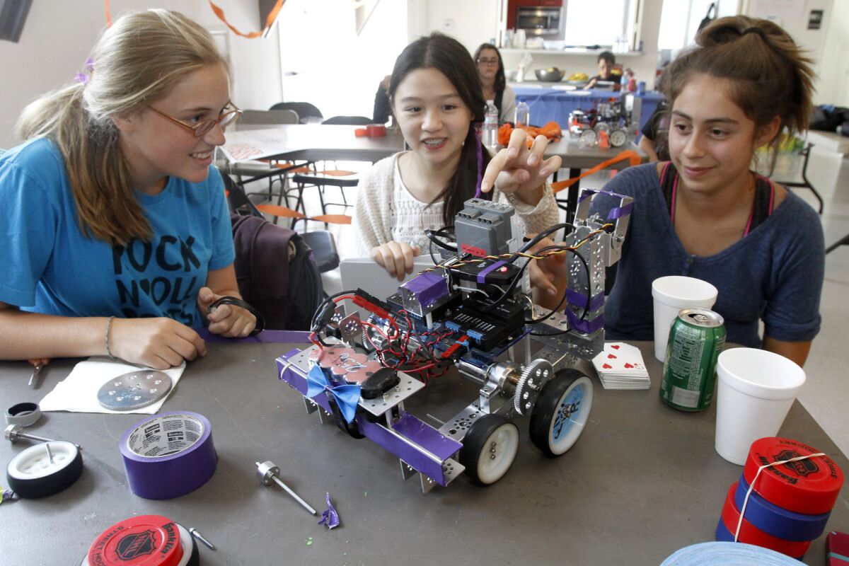 From left, Katherine Bishop, 14, of Sierra Madre, Isabella Lau, 13 of San Gabriel and Caterina Marchionne, 14 of San Gabriel, look over a robot they will rebuild to do a specific task, during robotics camp at the Girls Scouts of America Montrose office on Saturday, August 1, 2014.