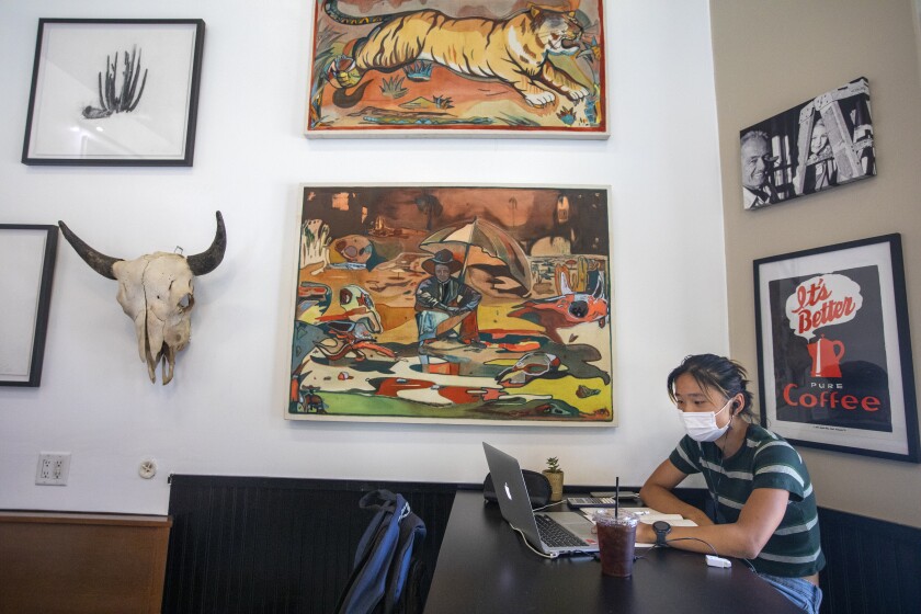 SOUTH PASADENA, CA - JULY 18: Lilian Zhu, 17, is working at her laptop wearing her face mask inside Charlie's Coffee House during the coronavirus pandemic on Sunday, July 18, 2021 in South Pasadena, CA. Once again the Los Angeles County on Sunday began requiring people to wear masks in indoor public places, opening a new battle line as the coronavirus is rising significantly among unvaccinated people. L.A. County is by far the biggest jurisdiction in the nation to require masks again. But with coronavirus cases rising across the nation largely because of the highly infectious Delta variant, officials elsewhere will be watching to see if the effort works. (Francine Orr / Los Angeles Times)