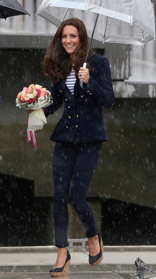 Duchess Catherine shelters herself from the rain as she and Prince William arrive to sail on Team New Zealand's America's Cup yachts on Auckland Harbor.