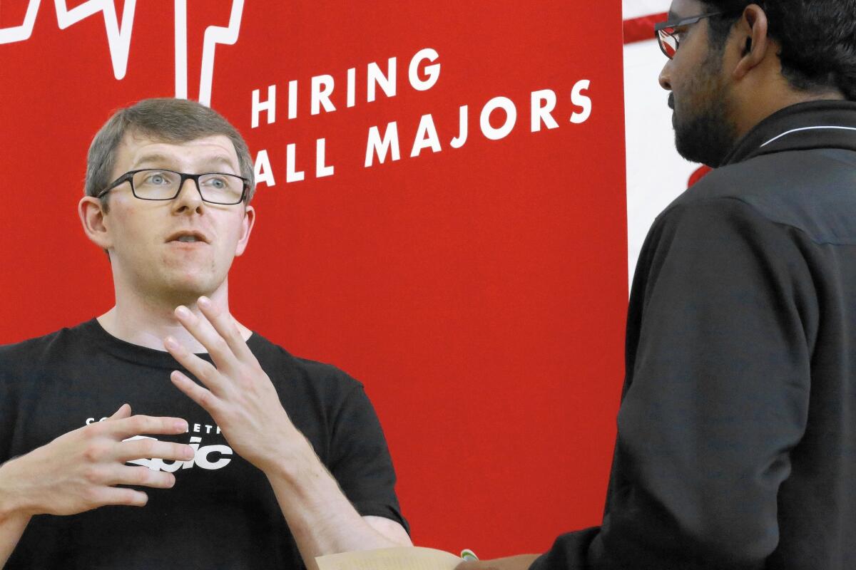 Jacob Robinson, left, of Epic, an electronic health record software company, speaks at a career fair in Illinois in September. U.S. firms are showing increased confidence in the economy.