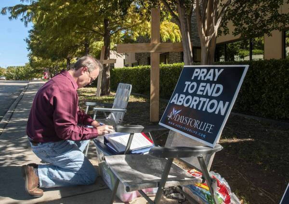 A man adds his name to a list of people holding a vigil outside an abortion clinic in Dallas.