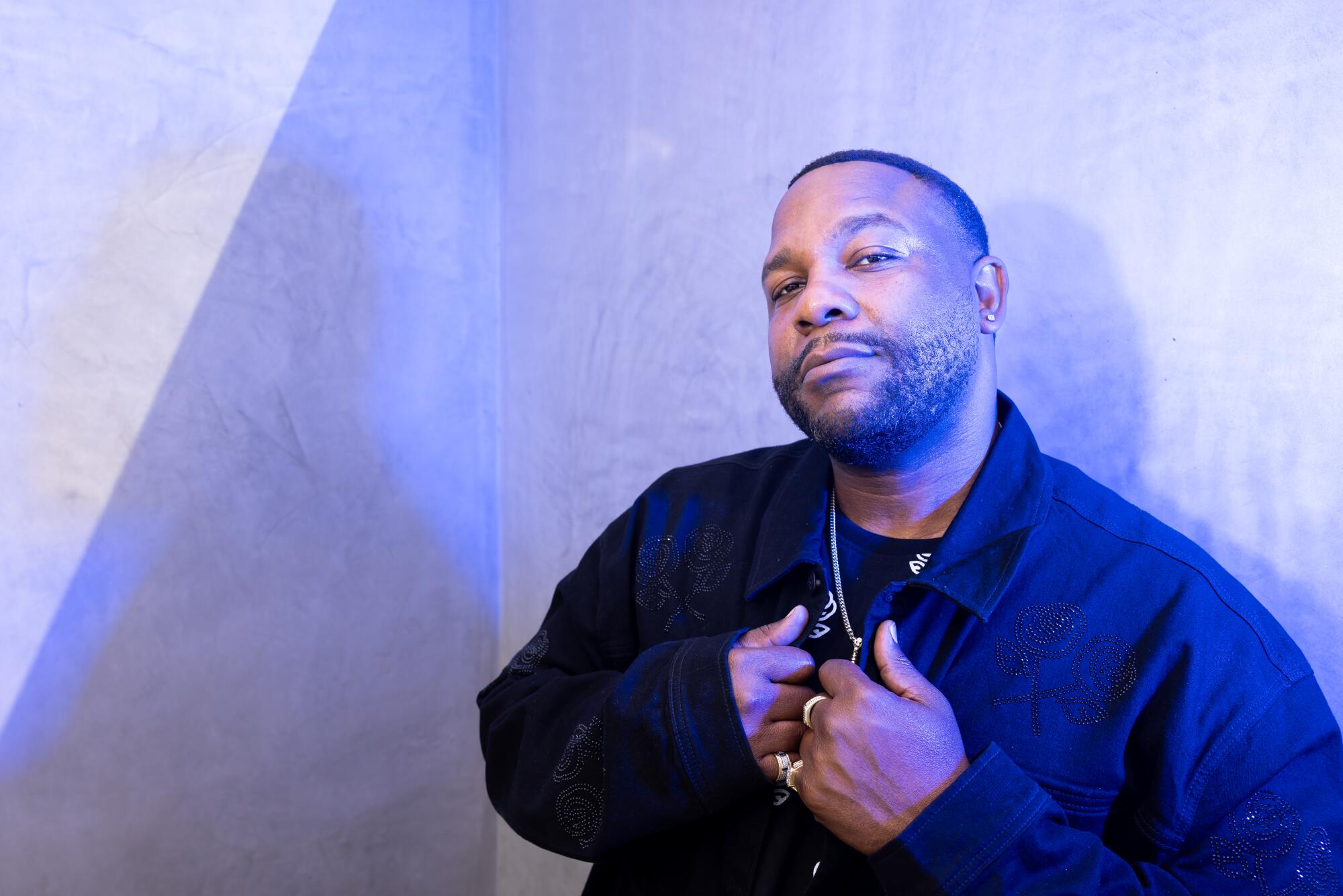 Man leaning against a concrete wall in a black jacket