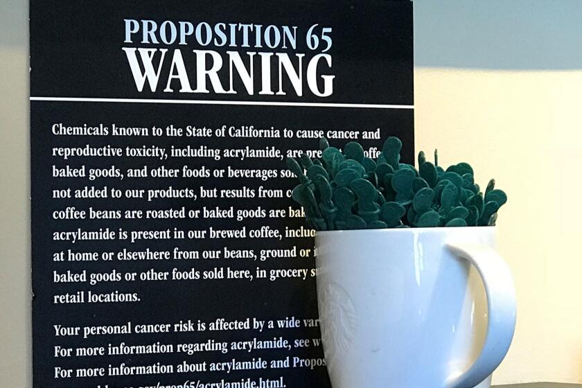 In this March 30, 2018, photo, a posted Proposition 65 warning sign is seen behind a coffee mug at a Starbucks coffee shop in Burbank, Calif. Superior Court Judge Elihu Berle has issued a final ruling requiring coffee to carry cancer warning labels in California. The Los Angeles judge issued his decision Monday, May 7, 2018, that Starbucks and other coffee companies failed to show that benefits from drinking coffee outweighed any risks. (AP Photo/Damian Dovarganes)