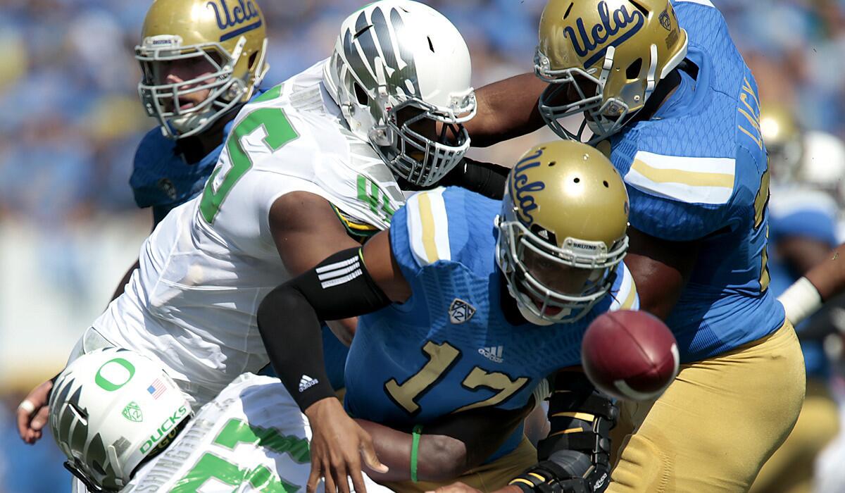 Bruins quarterback Brett Hundley watches the ball tumble away after he was hit by Ducks linebacker Tony Washington (91) and defensive lineman T.J. Daniel in the first quarter.