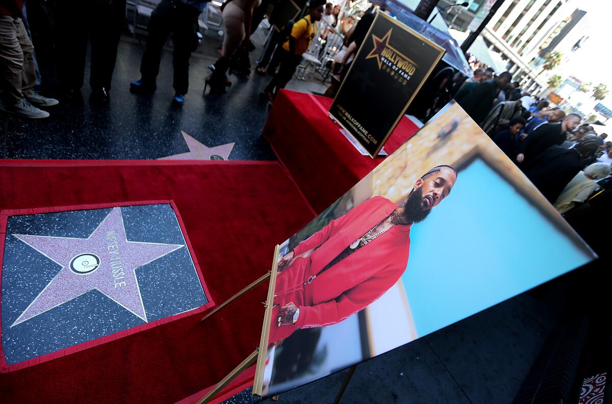 A photo portrait of Nipsey Hussle stands beside his new star on the Hollywood Walk of Fame.