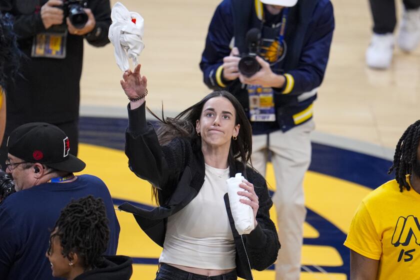 Indiana Fever player Caitlin Clark throws a tee-shirt to a fan during a time out during the first half between the Indiana Pacers and the Milwaukee Bucks in Game 2 in an NBA basketball first-round playoff series, Friday, April 26, 2024, in Indianapolis. (AP Photo/Michael Conroy)