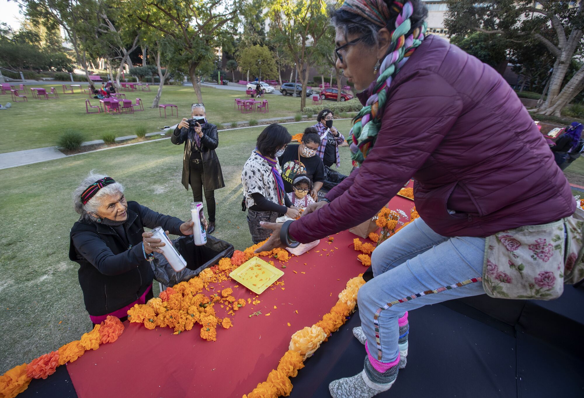 A woman hands candles to her daughter to place on an altar.