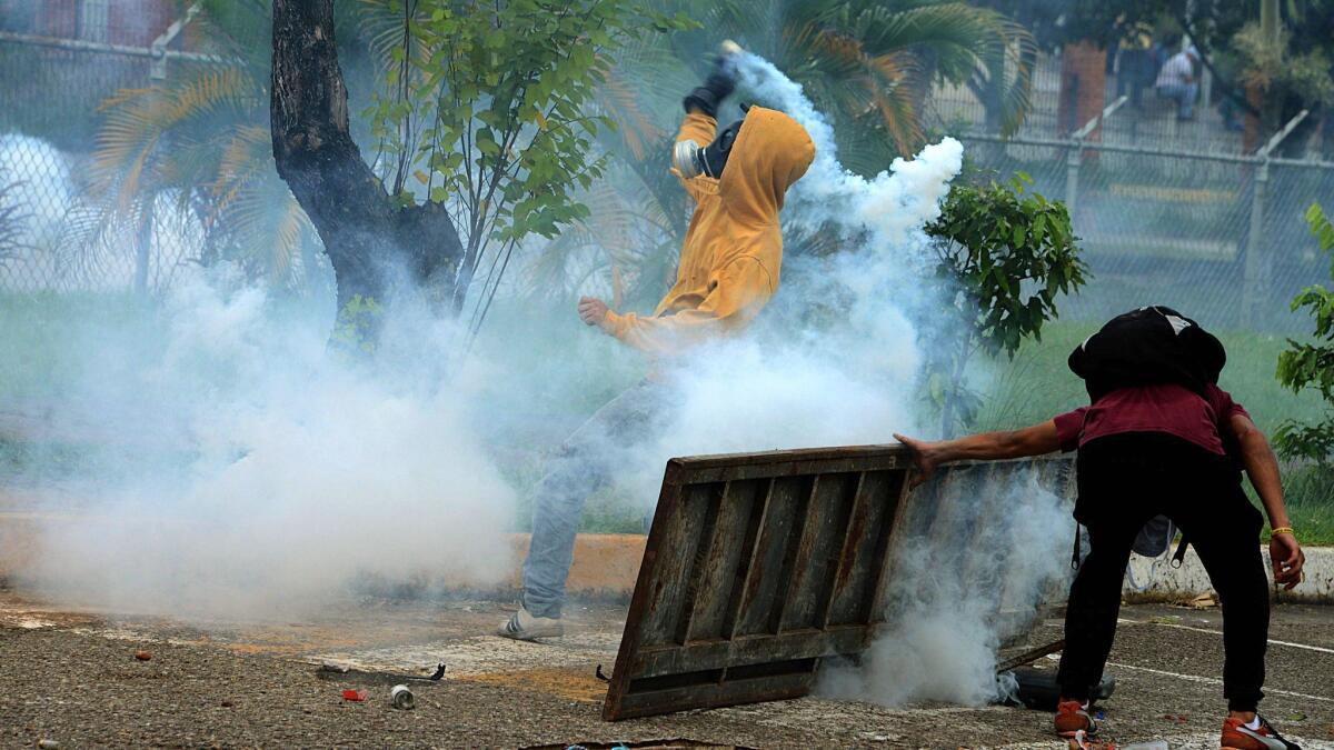 Students opposing Venezuelan President Nicolas Maduro wearing gas masks throw back tear gas grenades at police during a demonstration in San Cristobal, Venezuela, on April 5.