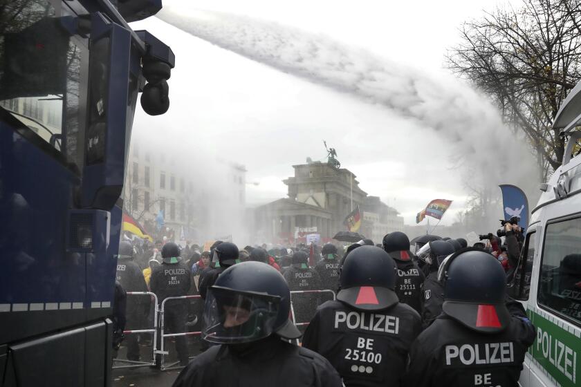 File - In this Wednesday, Nov. 18, 2020 file photo, police uses water canons to clear a blocked a road between the Brandenburg Gate and the Reichstag building, home of the German federal parliament, as people attend a protest rally in Berlin, Germany, against the coronavirus restrictions in Germany. Authorities in Germany say the number of far-right extremists in the country increased last year as neo-Nazis sought to join protests against pandemic-related restrictions. German Interior Minister Horst Seehofer said authorities counted 33,300 far-right extremists in 2020, an increase of almost 4% from the previous year. (AP Photo/Michael Sohn, file)