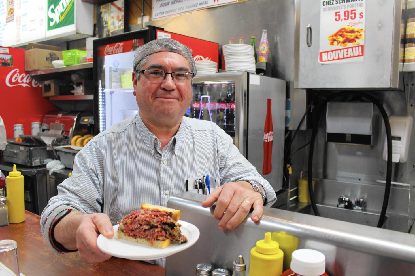 Joao Goncalves serves up one of Schwartz’s legendary smoked meat sandwiches — a half, actually — just as servers have done here since 1928.
