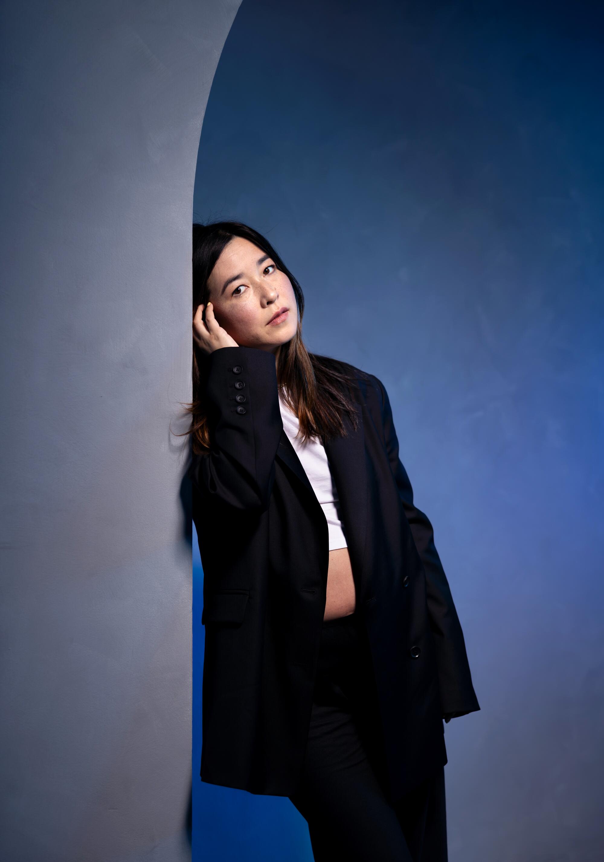 Maya Erskine leans against a wall for a portrait. 