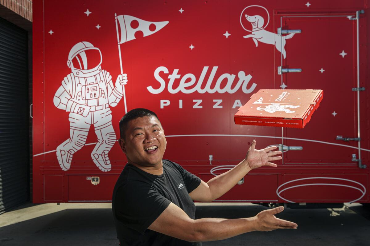 A man stands as a pizza box is aloft.