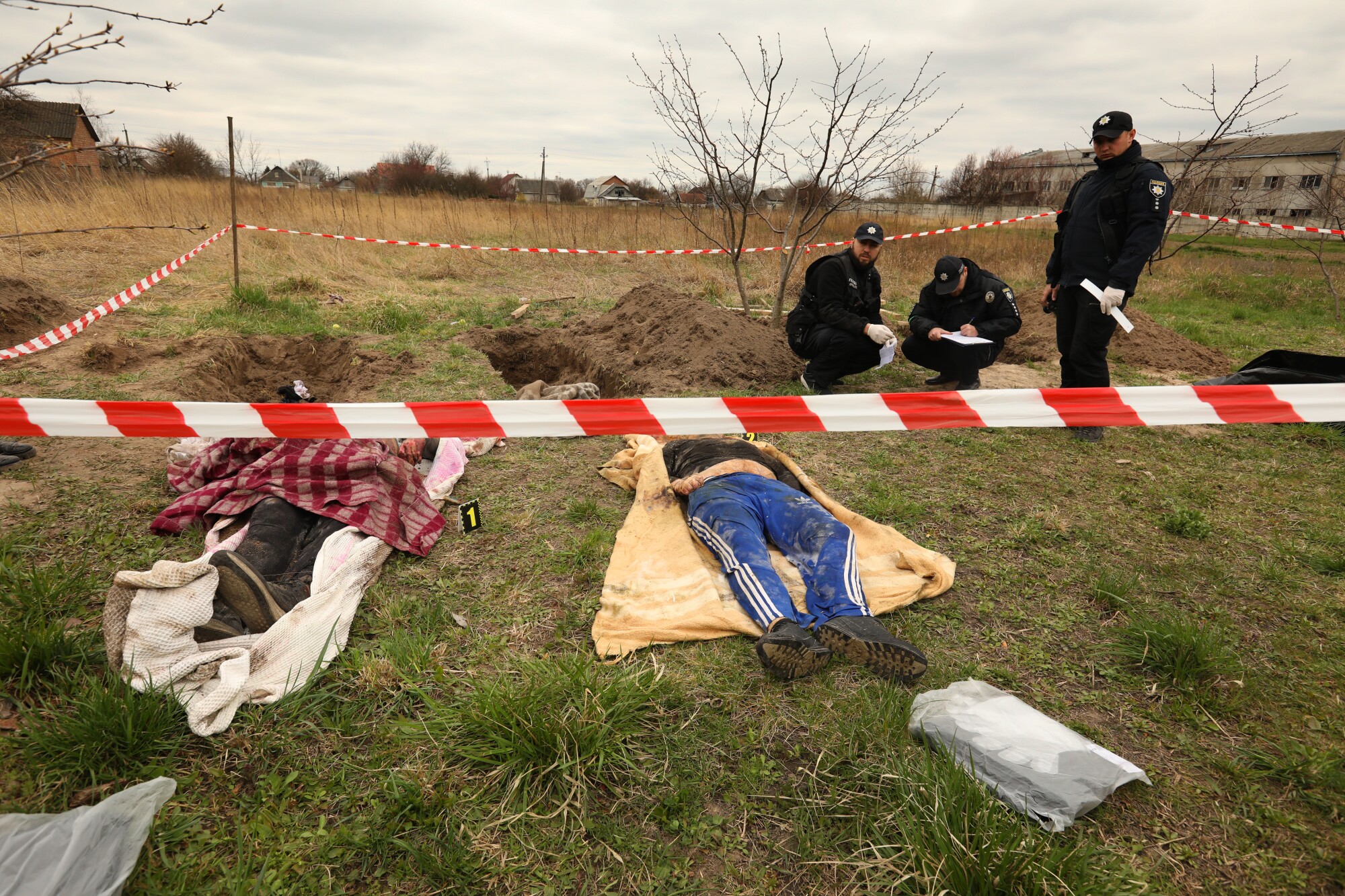 Bodies exhumed from a mass grave lie on the ground as investigators work in the town of Borodyanka, Ukraine.