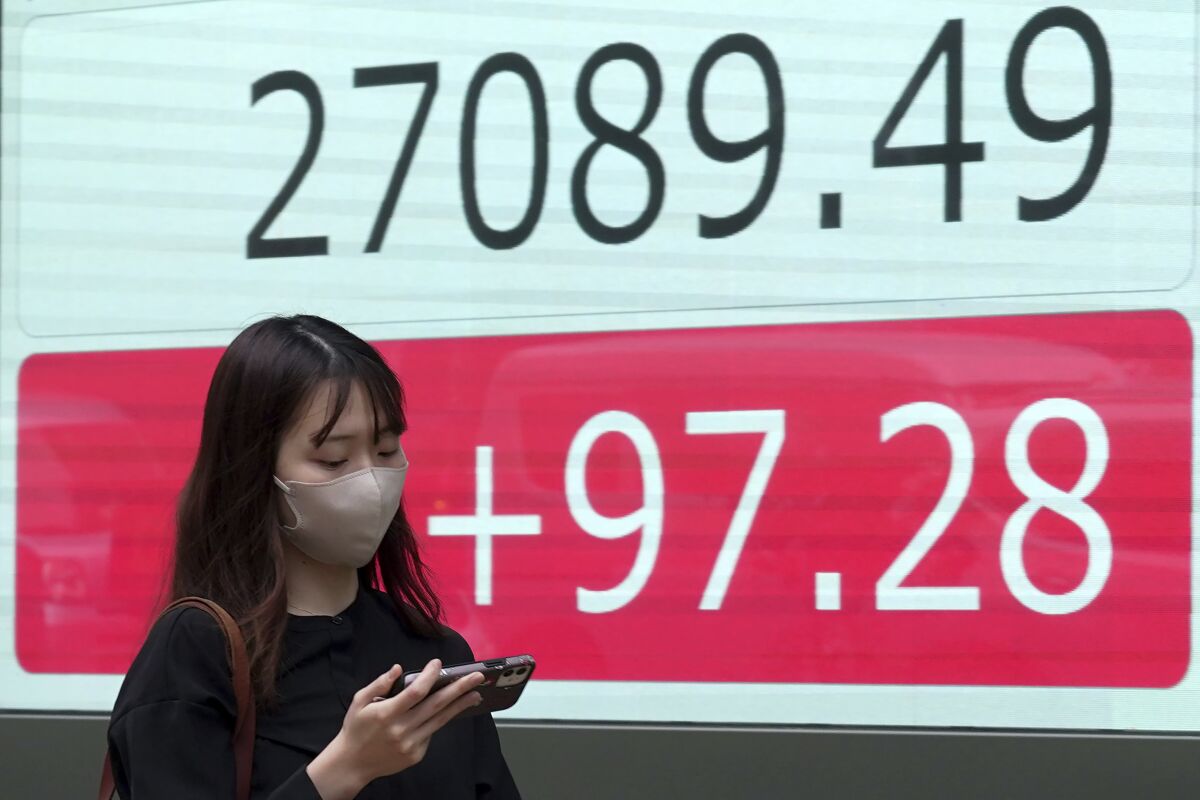 A person walks in front of an electronic stock board showing Japan's Nikkei 225 index at a securities firm Wednesday, Oct. 5, 2022, in Tokyo. Hong Kong’s share benchmark soared more than 5% on Wednesday as Asian shares tracked gains on Wall Street. (AP Photo/Eugene Hoshiko)