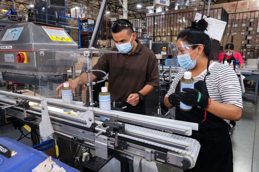 October 22, 2020, Vista, California_USA_| At Dr. BronnerOs All-One! soaps employees Rolando Martinez, left, and Ofelia Raymundo work on a machine bottling baby soap. |_Photo Credit: Photo by Charlie Neuman