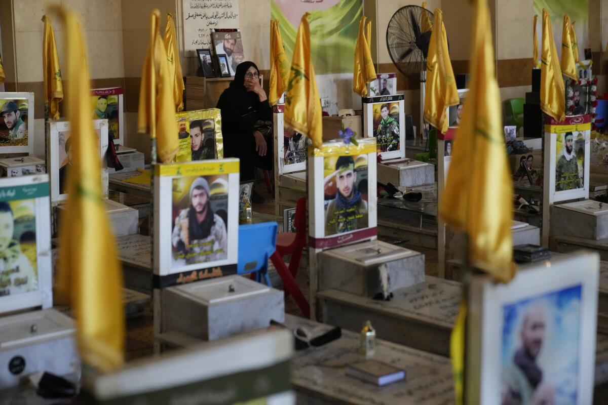 A woman sits in a cemetery as she visits the graves of killed Hezbollah members in the southern suburbs of Beirut, 