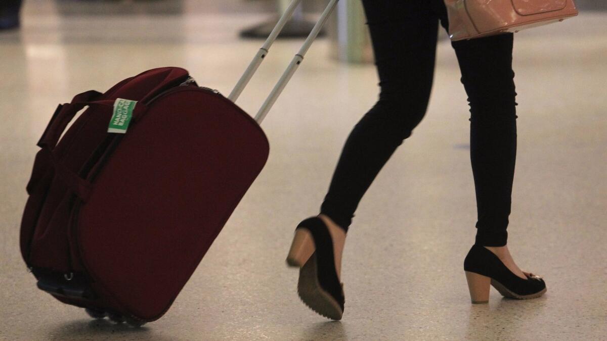 A traveler with a rolling suitcase arrives at Los Angeles International Airport.